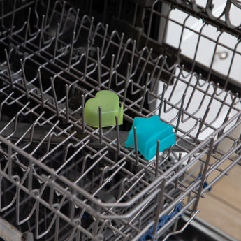 Two dipping cups from Bumkins Grip Dish Deluxe Infant 5-Piece Mealtime Set: Blue Jelly sit in the top rack of an open dishwasher.