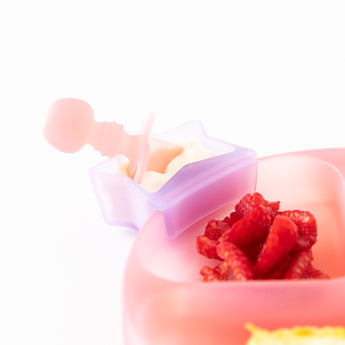 A Bumkins Silicone Little Dipper Combo 2 Pack: Magenta Jelly with yogurt and a baby spoon beside a pink bowl of berries on a white background.