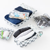 Close-up of Bumkins The Outfit Organizer Essential 5-Piece Set: Charcoal Check with clothes and toiletries on a white background.