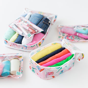 Close-up of Bumkins The Outfit Organizer Essential 5-Piece Set: Boots with clothes, makeup, and toiletries on a white background.