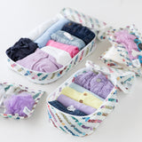 Close-up of Bumkins The Outfit Organizer Essential 5-Piece Set: Mickey & Friends Varsity with clothes and toiletries on a white background.