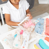 A child packs toiletries into a bag from Bumkins The Outfit Organizer Essential 5-Piece Set: Palm Daze on a white table.