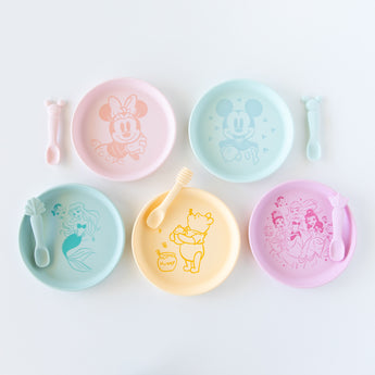 Bumkins Silicone Plate + Spoon Set: Disney Mickey Mouse sits among other similar plate and spoon sets on a white background.