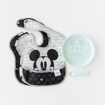 Bumkins Silicone Plate + Spoon Set: Disney Mickey Mouse sits next to waterproof bibs on a white background.