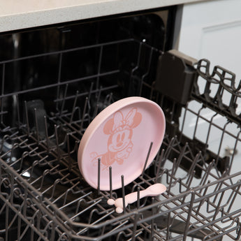 Bumkins Silicone Plate + Spoon Set: Disney Minnie Mouse sits in the top rack of an open dishwasher.