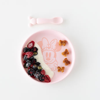Bumkins Silicone Plate + Spoon Set: Disney Minnie Mouse features a pink dish with yogurt, berries, and pancakes on a white background.
