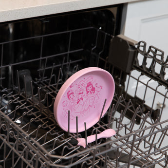 Bumkins Silicone Plate + Spoon Set: Disney Princess sits in the top rack of an open dishwasher.