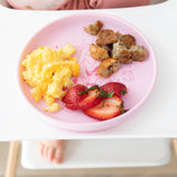 Bumkins Silicone Plate + Spoon Set: Disney Princess sits on a high chair tray with breakfast; a child's foot is visible underneath.