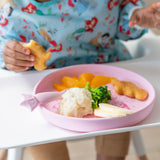 A child in a colorful bib enjoys nuggets, mashed potatoes, and fruit from Bumkins Silicone Plate + Spoon Set: Disney Princess.