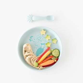 Bumkins Silicone Plate + Spoon Set: Disney Princess Ariel holds hummus, carrots, and cucumber stars on a white background.