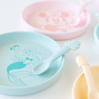 Bumkins Silicone Plate + Spoon Set: Disney Princess Ariel sits on a white background next to other similar plates.