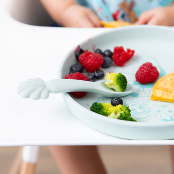 Bumkins Silicone Plate + Spoon Set: Disney Princess Ariel, filled with broccoli, berries, and a pancake, sits on a highchair tray.