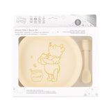 Bumkins Silicone Plate + Spoon Set: Disney Winnie the Pooh is shown in a packaging box, with a clear window displaying the plate and spoon.