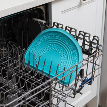 A placemat from Bumkins Baby-Led Weaning Essential 6-Piece Set: Blue sits in the top rack of an open dishwasher.
