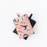 Bumkins Packable Tote Bag: Yoga Pals, folded in its pocket, is shown stacked on top of another bag on a white background.