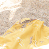 Close-up of Bumkins Reversible Roll & Go Blanket, Desert Boho covered in sand on a beach.