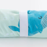 Close-up of a rolled Bumkins Reversible Roll & Go Blanket, Rolling with the Waves  on a white background, secured by a white elastic band.