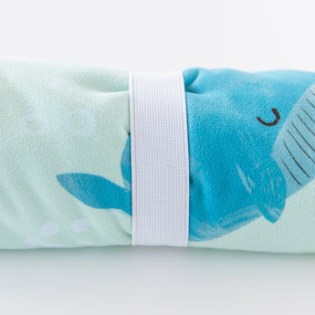 Close-up of a rolled Bumkins Reversible Roll & Go Blanket, Rolling with the Waves  on a white background, secured by a white elastic band.