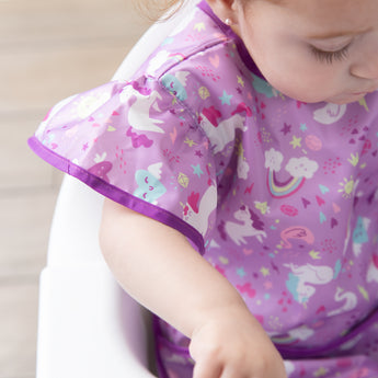Close-up of a child in a bib from Bumkins Snack In Style 3-Piece Set: Unicorns and Rainbows, with focus on the sleeve.