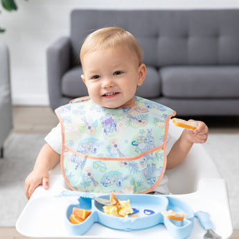 A young boy eats breakfast with Bumkins On-The-Go Mealtime 7-Piece Set: Stitch Star-ring Up Trouble in a cozy living room.