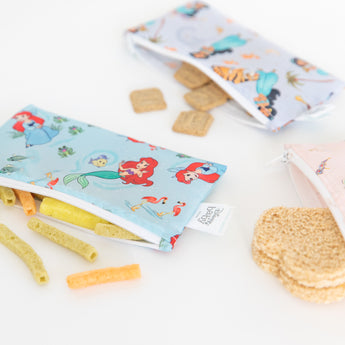 Close-up of bags from Bumkins Snack In Character 4-Piece Set: Disney Princess Magic Belle with snacks spilling out on a white background.