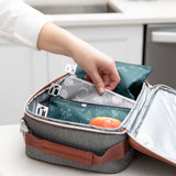 A hand places Roamio by Bumkins Reusable Snack Bag 4 Pack: Desert Night  in a lunch bag on a kitchen counter.