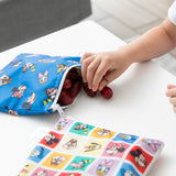 A child grabs grapes from a Bumkins Snack Bag 4 Pack: Mickey & Friends Excellent Eight next to another on a white table.