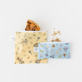 Two bags from Bumkins Snack Bag 4 Pack: Mickey + Minnie Mouse Brunch Bunch hold a quiche slice and granola pieces on a white background.