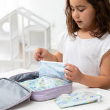 A young girl in a white shirt packs Bumkins Snack Bag 4 Pack: Stitch Star-ring Up Trouble in a purple lunch bag on a white table.