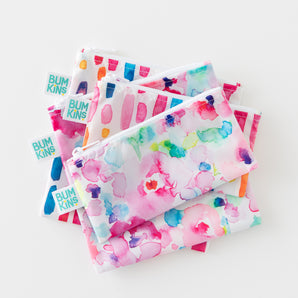 Four Bumkins Reusable Snack Bags in Watercolor & Brushstrokes designs, stacked on a white surface. 4-pack.