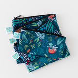 Four Bumkins reusable snack bags in jungle and animal prints are stacked on a white surface.