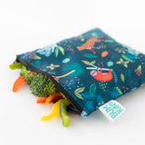 Fresh veggies spill from an open Bumkins Reusable Snack Bag, Large 2-Pack: Jungle & Animal Prints on a white background.