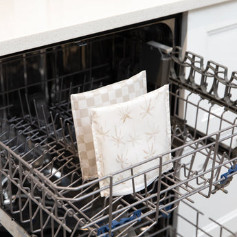 Bumkins Reusable Snack Bag, Large 2 Pack: Palm Check sit in the top rack of an open dishwasher in a kitchen setting.
