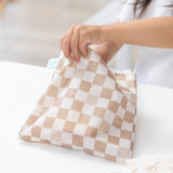 A child reaches into a Bumkins Reusable Snack Bag, Large 2 Pack: Palm Check at a white table.