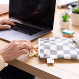 A hand reaches for popcorn from a Roamio by Bumkins Bumkins Reusable Snack Bag, Large 2 Pack: Double Check next to a laptop on a desk.