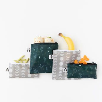 Roamio by Bumkins Reusable Snack Bag 4 Pack: Desert Night lays overlapped on a white background with wraps, fruit, and snacks inside.