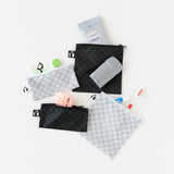 Roamio by Bumkins Snack Bag 4 Pack: Rich & Boujee is messily arranged on a white background with toiletries peeking out.