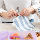 Close-up of hands packing a lunch in Bumkins Lunchbox Legends 6-Piece Set: Coastal Purple Jelly.