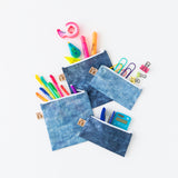 Roamio by Bumkins Snack Bag 4 Pack: Denim On Denim is messily arranged on a white background with office supplies peeking out.