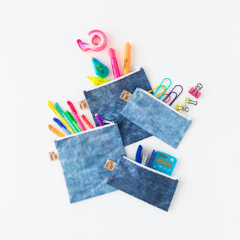 Roamio by Bumkins Snack Bag 4 Pack: Denim On Denim is messily arranged on a white background with office supplies peeking out.