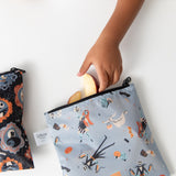 Close-up of a child reaching for apple slices in bags from Bumkins Snack In Character 3-Piece Set: Disney Everyday Is Halloween Jack.