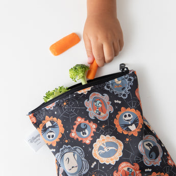 Close-up of a child reaching for veggies from a bag from Bumkins Snack In Character 3-Piece Set: Disney Everyday Is Halloween Jack.
