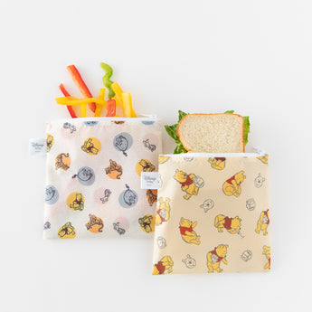 Bumkins Reusable Snack Bag 4 Pack: Disney Pooh Bear + Friends holds bell pepper slices and sandwiches on a white background.