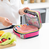 A person packs a lunch bag on a kitchen counter with Bumkins Lunchbox Legends 6-Piece Set: Disco Pink Jelly.