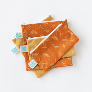 Set of four Bumkins Desert Boho reusable snack bags, orange and yellow with white geometric patterns, stacked on white.