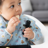 Close-up of a child chewing fruit while holding a utensil from Bumkins Grip Dish Essential Infant 3-Piece Mealtime Set: Disney Mickey Mouse.