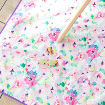 A utensil from Bumkins First Foods Essential 5-Piece Mealtime Set: Green Jelly lays on a floral mat next to pieces of pancake.