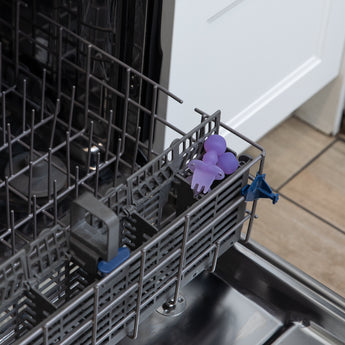 Bumkins Silicone Chewtensils®: Purple Jelly sit in the utensil compartment of an open dishwasher.