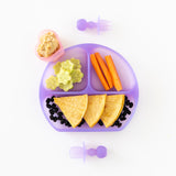 Bumkins Silicone Chewtensils®: Purple Jelly on a white background next to a purple plate with tortillas, carrots, cucumber, beans & hummus.
