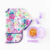 A floral baby bib with Bumkins Silicone Chewtensils®: Purple Jelly, a purple bowl with spaghetti, and a spoon on a white background.